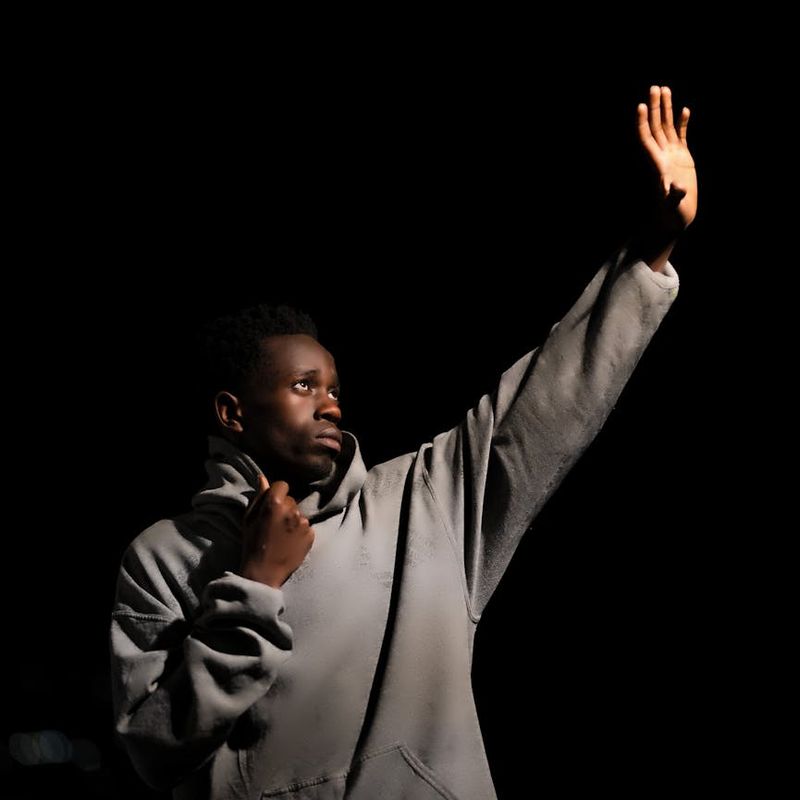 A man's silhouette performing a controlled movement against a dark background.
